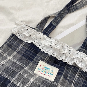 Detail of blue plaid tote bag with white lace trim and Happy slogan patch design