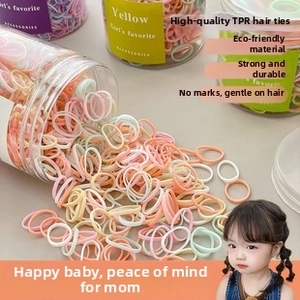Bulk macaron colored TPR elastic hair ties pouring out of a large plastic storage jar