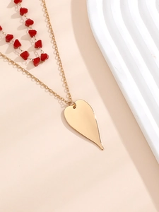 Vue macro du pendentif cœur doré avec des perles rouges facettées sur la chaîne
