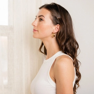 Elegant gold hoop earrings and minimalist hair clip worn by a model in soft light