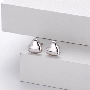 Detailed close-up of polished 925 sterling silver heart studs on white display blocks