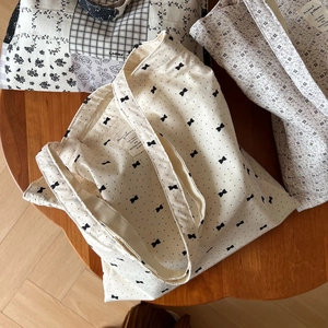 Detailed top view of three cotton canvas tote bags with floral and bow patterns on wood table