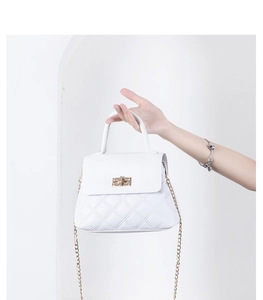 Detail of white quilted handbag featuring gold twist lock and metallic chain strap