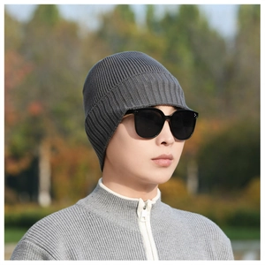 Detailed close-up of dark grey ribbed knit beanie with protective ear flaps for winter