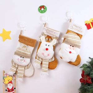 Three plush Christmas stockings with Santa, Reindeer, and Snowman hanging on a festive wall