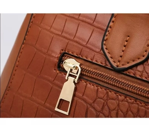 Macro shot of brown crocodile embossed leather with premium gold metal zipper detail