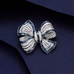 Elegant silver bow brooch with blue square crystals and pave-set shimmering clear gemstones