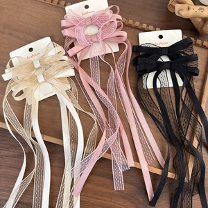 Detailed macro view of lace bow hair clips with long ribbons in cream, pink and black