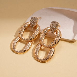 Detail of interlocking golden hoops with textured finish and zircon heart studs