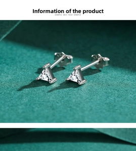 Macro shot of silver triangle cut zircon stud earrings on deep green textured surface