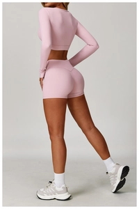 Side view of pink tight-fitting yoga set featuring long sleeve crop top and high waist shorts