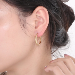 Close-up of a gold-plated stainless steel hoop earring featuring a textured mesh pattern