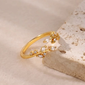 Elegant 18K gold plated leaf ring with sliding zircon crystals on beige stone background