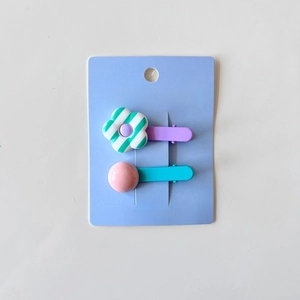 Detail of two cute flower and round bead hair clips for girls on a blue paper card