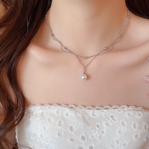 Gros plan d'un collier double épaisseur en argent avec détail dentelle et perle blanche
