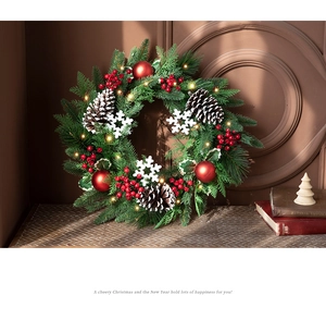 Close-up of 40cm Christmas wreath with red berries and warm LED lights on a vintage wall