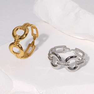 Detailed shot of gold and silver chain link rings on a white minimalist stone base