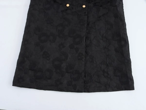Detail of black jacquard fabric texture with floral patterns and gold buttons on the coat