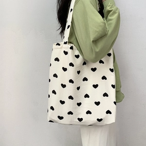 Close-up of heart pattern tote bag on model's shoulder with clean white background