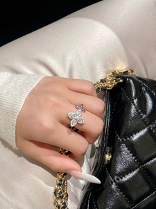 Close-up of elegant zircon butterfly ring on model hand holding a black quilted handbag