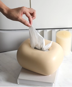 Vue détaillée d'une boîte à mouchoirs crème en céramique sur une table en marbre