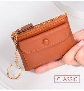 Detailed view of a brown leather coin purse with golden zipper and keychain held by hand
