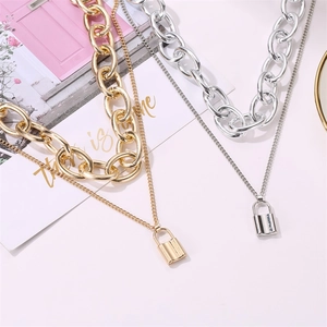 Detail of gold and silver chunky punk necklaces with layered chains and lock pendants