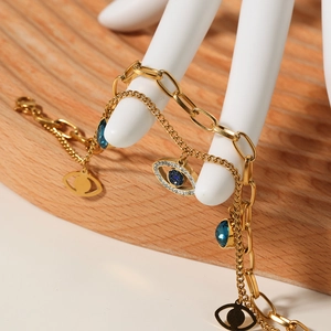 Gold double-layer Evil Eye bracelet with blue charms on a wooden background
