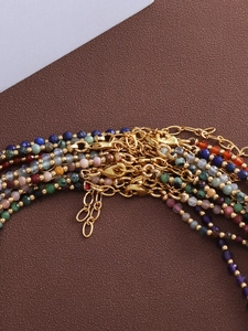 Macro detail of natural stone bead necklaces with colorful faceted gems and gold accents