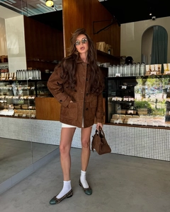 Street style view of a brown suede jacket paired with white skirt and handbag