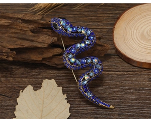 Macro detail of vintage snake brooch with blue rhinestones and antique gold finish