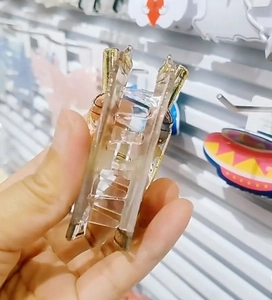 Detail view of a translucent acrylic hair claw clip with golden metal spring and wave teeth