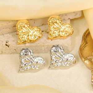 Detail of heart stud earrings in gold and silver with lava textured metal finish