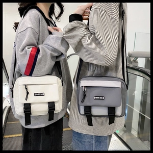 Detail of canvas crossbody bags in white and grey with buckles and front zippers