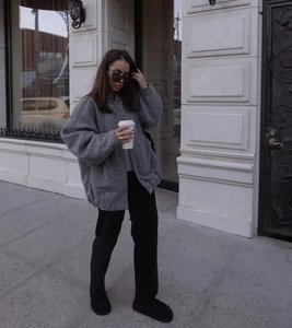 Street style shot of a woman in an oversized grey jacket and casual black pants