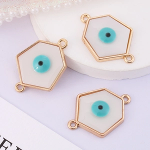 Detailed macro view of three white hexagonal evil eye charms with gold enamel finish