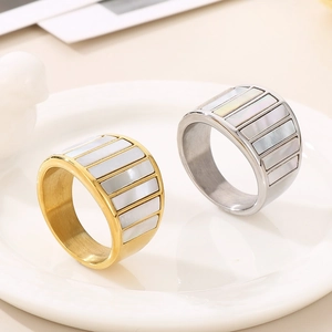 Macro shot of stainless steel rings with rectangular white shell inlay on a ceramic plate
