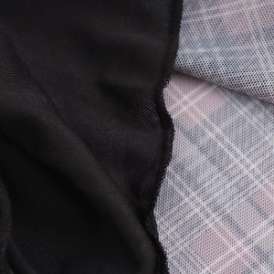 Detalle de tela de punto negra y tul con cuadros lilas en el vestido largo