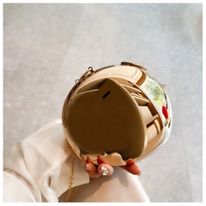 Close-up of golden spherical metal evening clutch bag with glossy mirror finish and chain