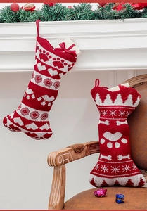 Detail of red and white knitted Christmas stockings with paw prints on a fireplace