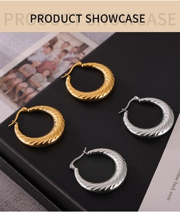 Macro detail of twisted texture gold and silver hoop earrings on a black display box