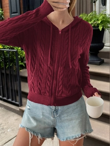 Detail of burgundy cable knit hoodie with pink zipper and ribbed cuffs on model