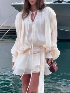 Detail of ivory chiffon dress featuring lantern sleeves with pearl buttons and pleats