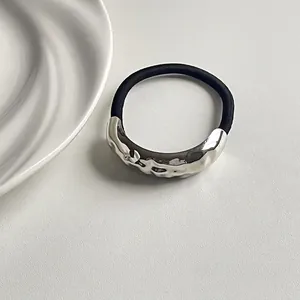 Minimalist silver geometric wavy metal elastic hair tie on textured cream background