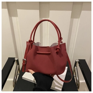 Detail of red PU leather bucket bag featuring unique knotted handle and soft matte finish