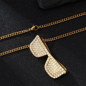 Macro detail of golden sunglasses pendant with white rhinestones and link chain
