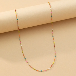 Macro detail of a gold link chain necklace featuring vibrant multi-colored enamel beads