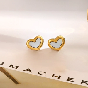 Close-up of heart-shaped gold stud earrings with elegant white mother of pearl inlay