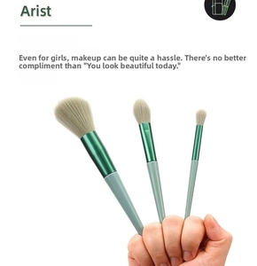 Detailed view of three green gradient makeup brushes held in hand for precision application