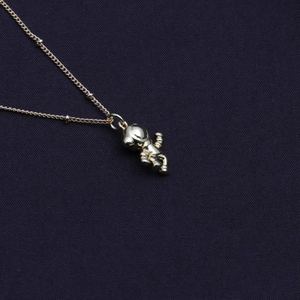 Gold plated astronaut pendant necklace with fine chain for women on dark blue fabric